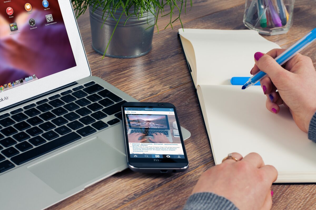 a Desk with a laptop, mobile phone and a womans hand