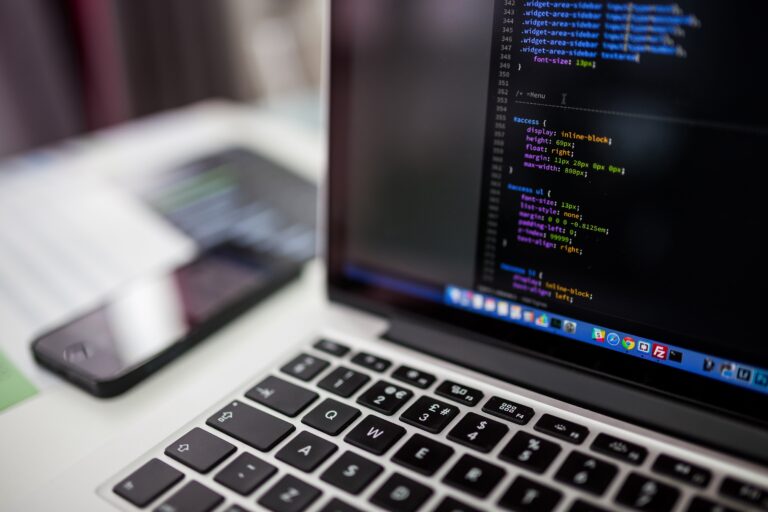 Macbook with code on screen on a desk.